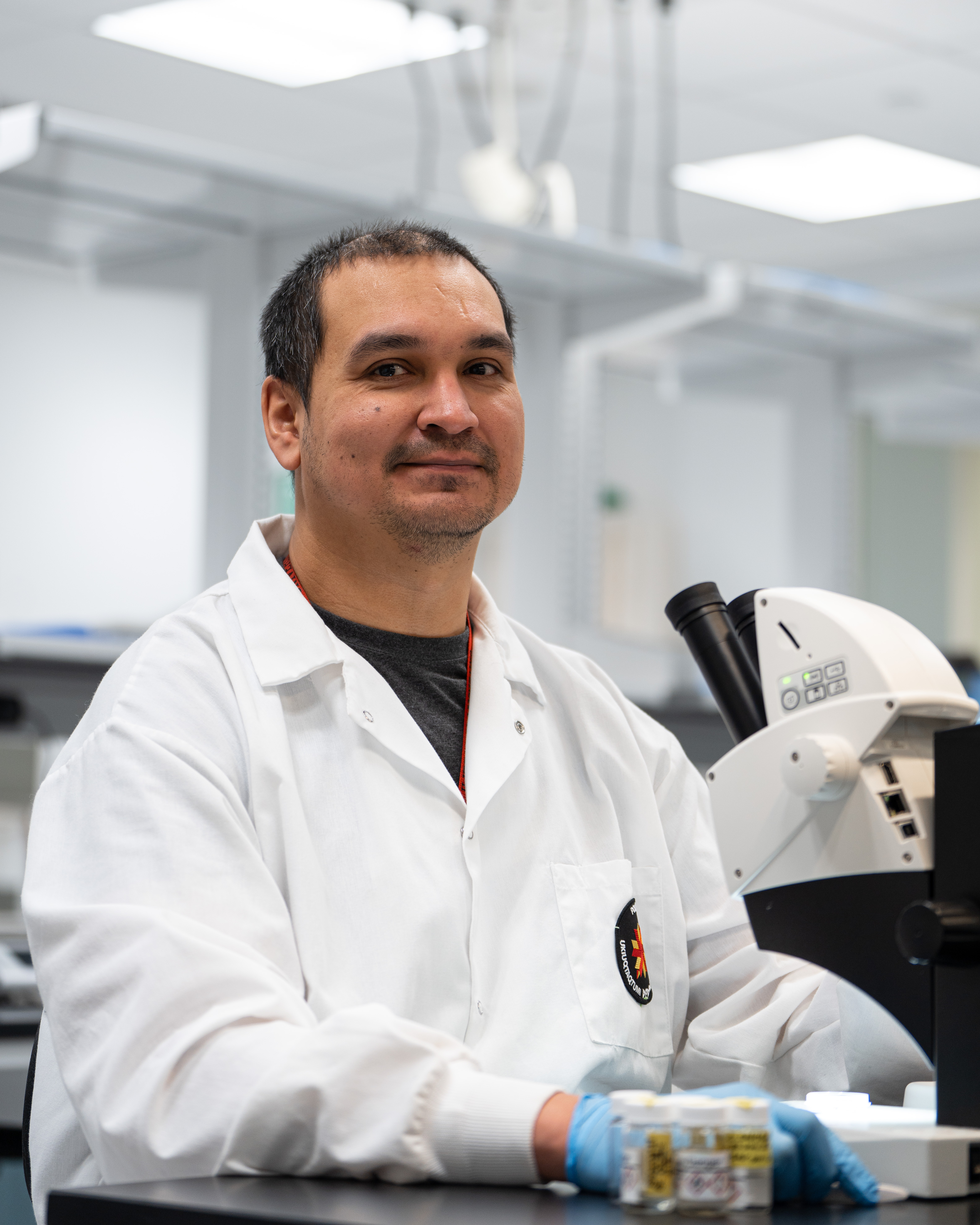 Photo headshot of man, in a lab coat, smiling.